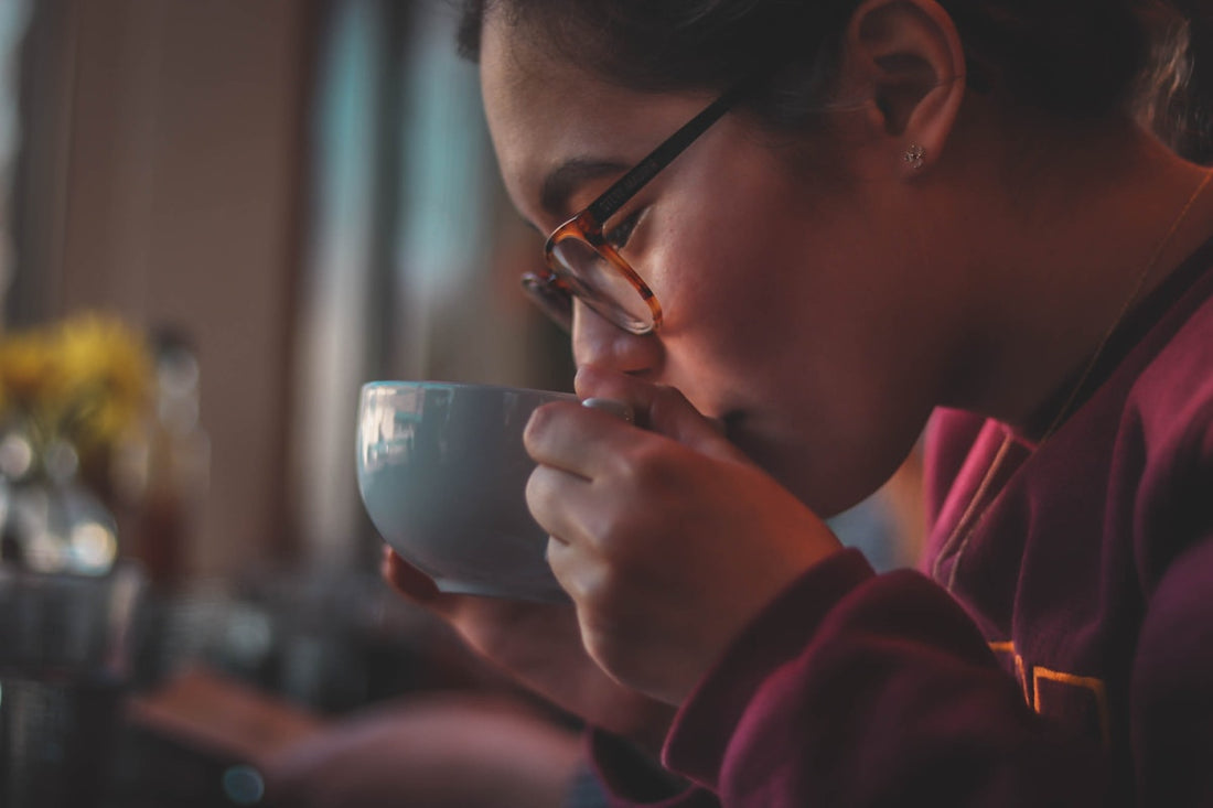 Femme avec lunettes savourant tranquillement une tasse de cafe decafeine