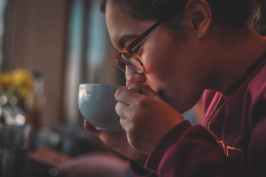 Femme avec lunettes savourant tranquillement une tasse de cafe decafeine