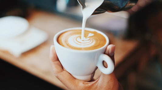 Barista versant du lait pour creer un art latte dans une tasse de cafe de specialite