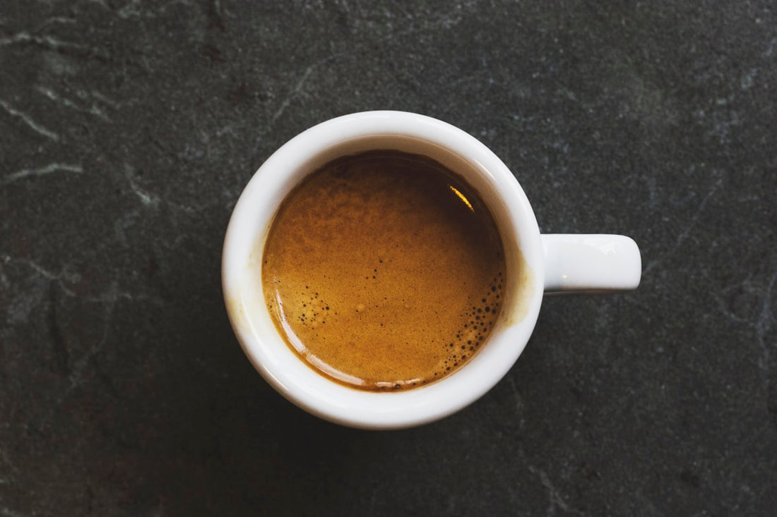 Espresso vu de dessus avec son crema doré dans une tasse blanche sur fond ardoise